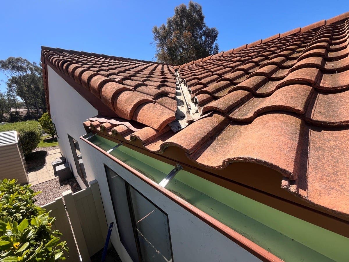 Long rolled gutter run below a tile roof valley